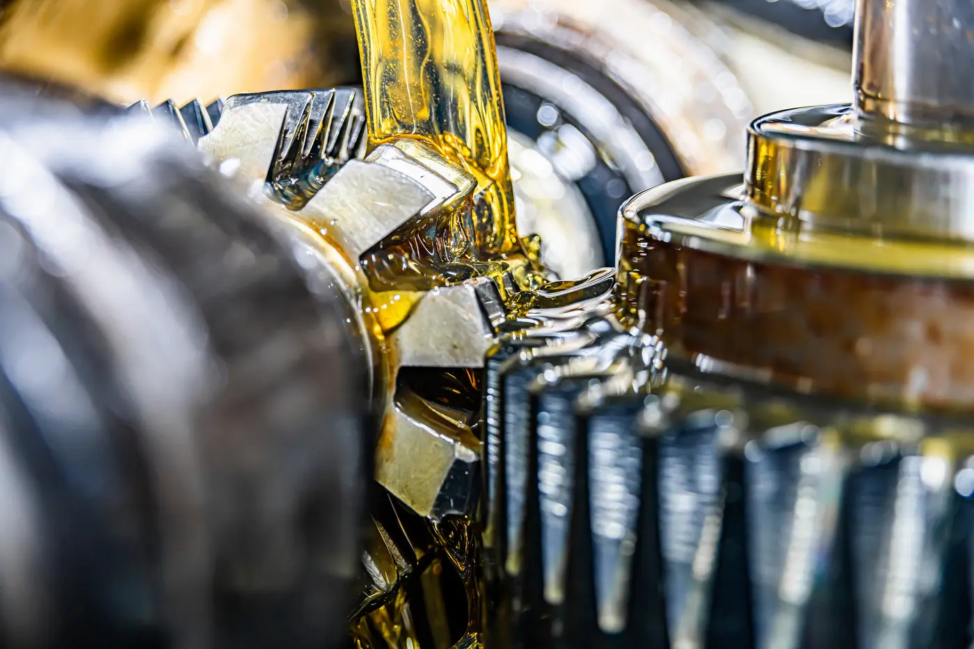 Macro shot of golden lubricant flowing over gear teeth